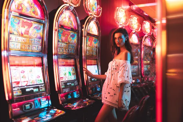 A stylish woman beside vibrant slot machines displaying glowing sevens, showcasing the variety of top slots at WAGIPLUS.